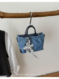 Detail view of a vintage blue denim handbag with silver star and balloon dog accessories