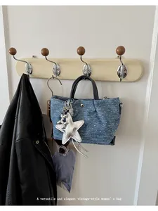 Vintage blue denim dumpling handbag with silver star charm hanging on a wall hook