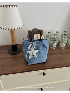 Versatile blue denim handbag featuring a stylish silver star charm in an elegant setting