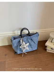 Detail view of a vintage-style blue denim handbag with a silver star charm