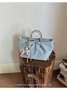 Vintage denim dumpling bag with silver handles and star charm on a wooden stump.