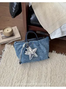 Blue denim tote bag detail featuring shiny silver star and balloon dog charm accents