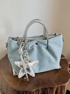 Casual light blue denim handbag with silver studs and star charm on a wooden stump