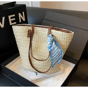 Sac cabas en paille tissé main avec ruban rayé bleu présenté dans sa boîte cadeau