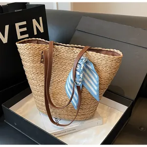 Gros plan sur un sac de plage en paille tissé à la main avec un foulard en soie rayé bleu élégant