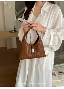 Elegant brown woven bucket bag with silver clasp held by a model in a retro vibe