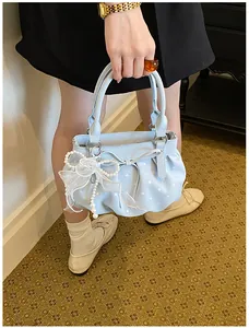 Detailed view of sweet light blue polka dot bucket bag with a white bow and pearl charm