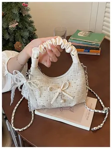 Détail du sac croissant en tweed crème avec poignée froncée et nœud en perles