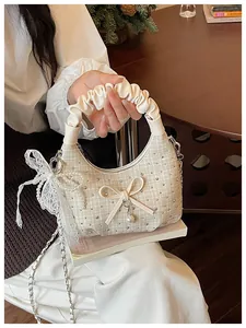 Détail d'un sac hobo en tweed crème avec poignée plissée et élégant pendentif en nœud de perle