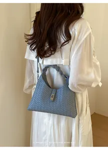 Detailed back view of a model wearing a light blue woven shoulder bag with a braided handle