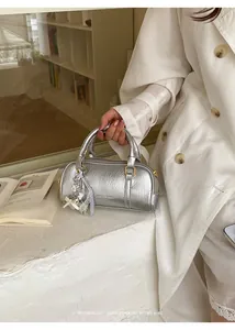 Detailed macro view of the metallic silver pillow handbag with elegant ribbon charm detail
