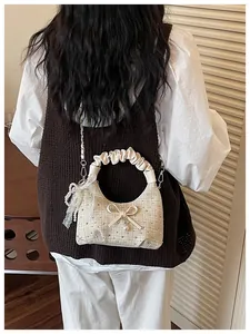 Sac hobo plissé beige tendance avec nœud et perle porté par un mannequin