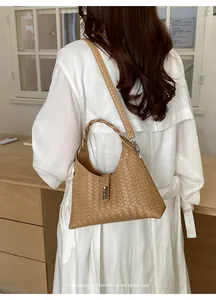 Minimalist tan woven bucket bag detail shown being worn over a stylish white linen coat