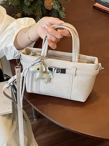 Elegant cream crinkled leather handbag with horse charm and adjustable crossbody strap