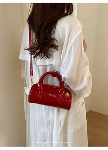 Detail view of a vibrant red mini pillow bag for women worn with a white trench coat.