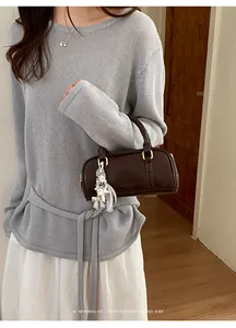 Asian model wearing a grey sweater holding a sophisticated brown leather pillow bag
