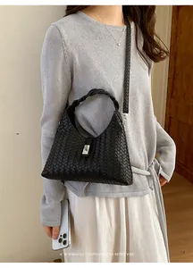 Macro view of a sophisticated black woven leather bucket bag with a sleek metal buckle