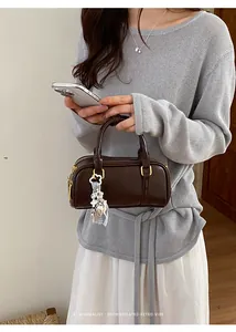 Stylish brown retro pillow bag detail featuring a flower charm and gold hardware accents.