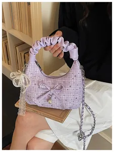 Vue détaillée d'un sac à main en tweed lilas avec poignée plissée et nœud en perles.
