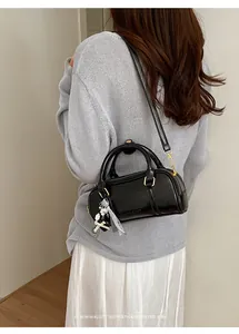 Close-up detail of a stylish black patent leather pillow bag with bow accessory.