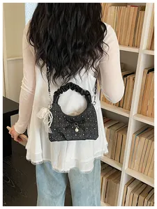 Détail d'un sac demi-lune au design unique avec poignée froncée et nœud décoratif