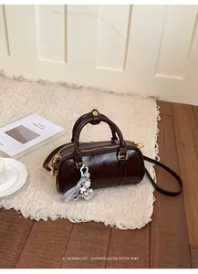 Vintage-style brown glossy pillow bag with heart charm on a textured white rug