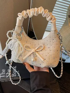 Sac hobo beige à poignée plissée avec strass brillants et nœud en perles.