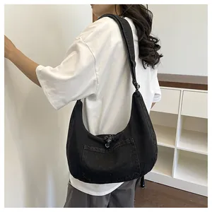 Detail view of black denim hobo bag worn by a model in casual white t-shirt.