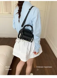 Vue arrière d'un sac à main noir à pois avec dentelle et un petit charme de chien
