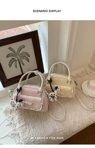 Zartrosa und cremefarbene Handtaschen mit Spitzenbesatz und Dalmatiner-Anhängern auf Teppich.