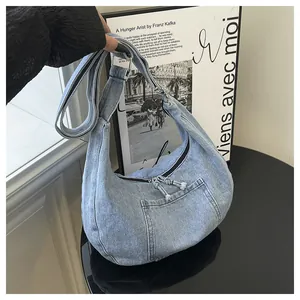 Close-up detail of a light blue denim hobo bag with front pocket and adjustable strap.