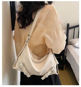 Détail d'un grand sac cabas blanc crème porté à l'épaule par un mannequin chic