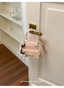 Detailansicht einer rosa Handtasche mit Spitzenbesatz und Dalmatiner-Anhänger an einer Tür
