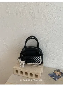 Détail du sac à main noir avec dentelle à pois et charmant pendentif de chien