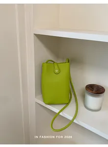 Dettaglio di una borsa a tracolla per cellulare in pelle verde lime su scaffale bianco
