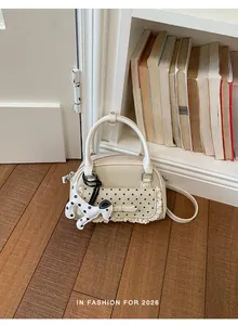 Detailansicht der cremefarbenen Handtasche mit Punktmuster, Spitze und Hundeanhänger
