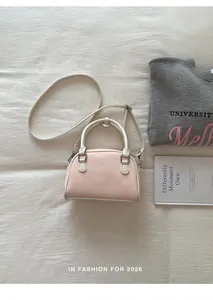 Detailansicht einer trendigen Handtasche in Rosa und Creme auf weichem Hintergrund.