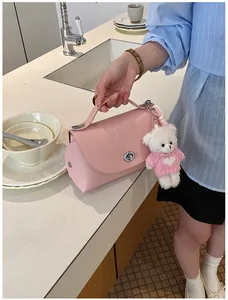 Elegant pink pebbled leather crossbody bag with white teddy bear charm in lifestyle scene