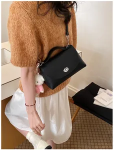 Detail view of a black vintage pebble leather handbag with a cute plush bear charm
