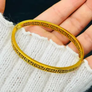 Close-up of 18k gold plated bracelet with intricate Greek key pattern detail.