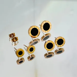 Macro view showing detailed rose gold Roman numeral stud earrings with black center inlay