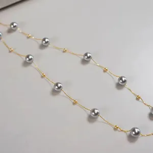 Close-up detail view of elegant grey pearl necklace with gold plated steel chain.