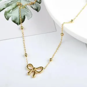 Macro detail of a high-end gold plated titanium steel bow pendant necklace for women.