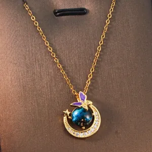Detailed macro view of golden crescent moon and blue galaxy planet pendant necklace