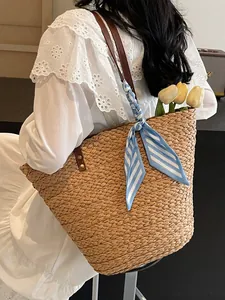 Grand sac de plage en paille tressée avec foulard rayé et anses en cuir pour l'été.
