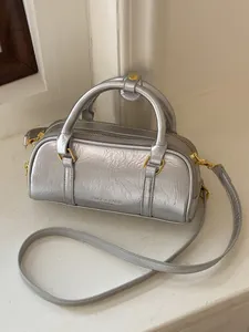Stylish metallic silver wrinkled pillow handbag with gold accents and a crossbody strap