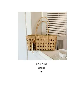 Detail view of a beige woven hollow-out tote bag with elegant beaded tassel charm