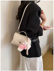 Detail shot of a cream-white textured leather crossbody bag styled with a black blazer.