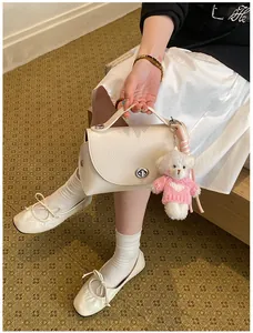 Detailed view of cream textured handbag with cute white bear plush keychain accessory