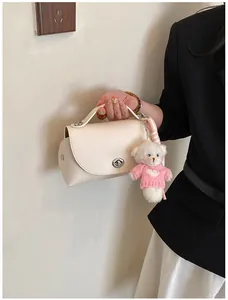 Close-up of cream textured leather handbag with cute bear charm and turn-lock